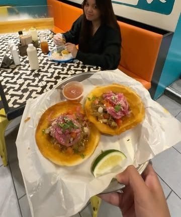 A guest holding fresh tostadas over El Poco’s patterned table
